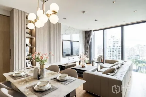 Condominium for rent in Khlong Toei, Bangkok - Open living and dining area with chandelier lighting, L-shaped sofa, and floor-to-ceiling windows overlooking the city skyline near Thonglor BTS.