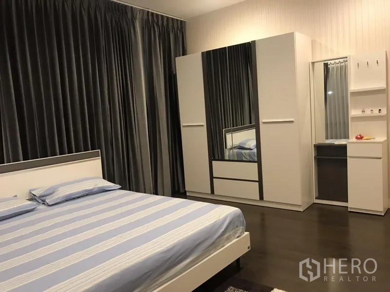 Detached House for rent in Bang Kapi, Bangkok - Second bedroom with striped bedding, mirrored wardrobe and dressing table.