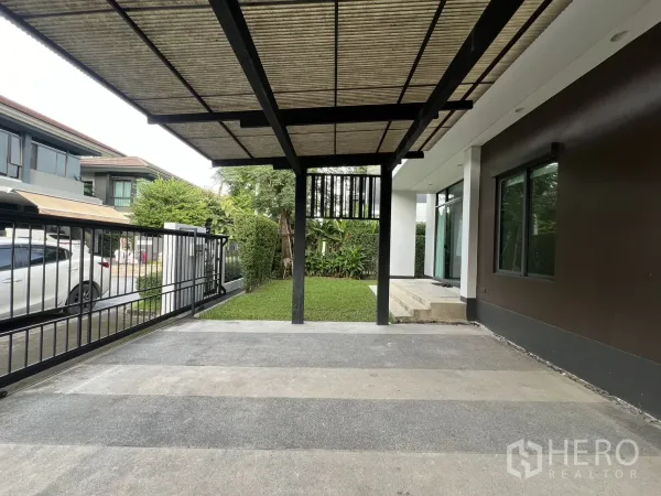 Detached House for rent in Bang Kapi, Bangkok - View from the carport toward the street with the gate and a small garden.