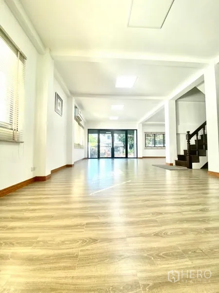 Townhouse for rent in Prawet, Bangkok - Spacious ground-floor living area with sliding glass doors and dark wood stairs.