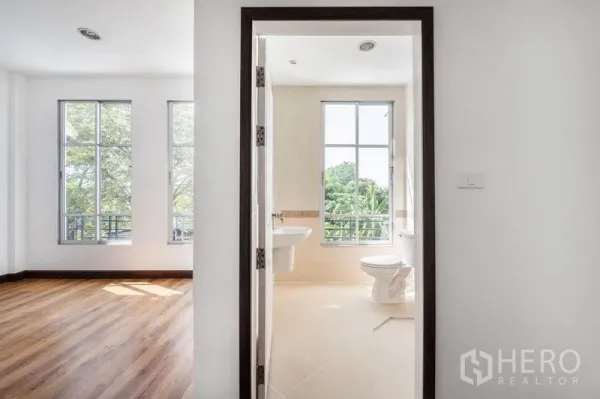Townhouse for sale - Bedroom entry to an ensuite bathroom, with tall windows overlooking greenery.