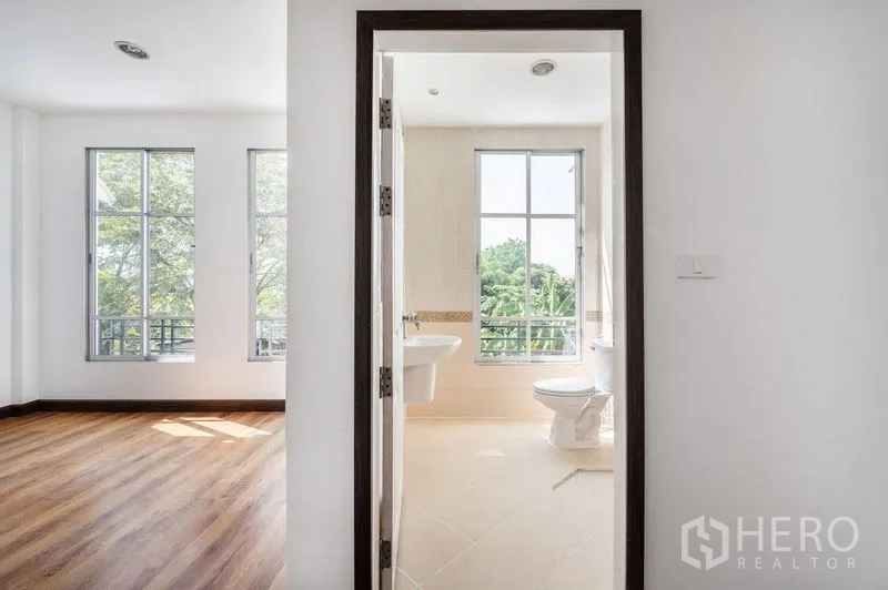 Townhouse for sale - Bedroom entry to an ensuite bathroom, with tall windows overlooking greenery.