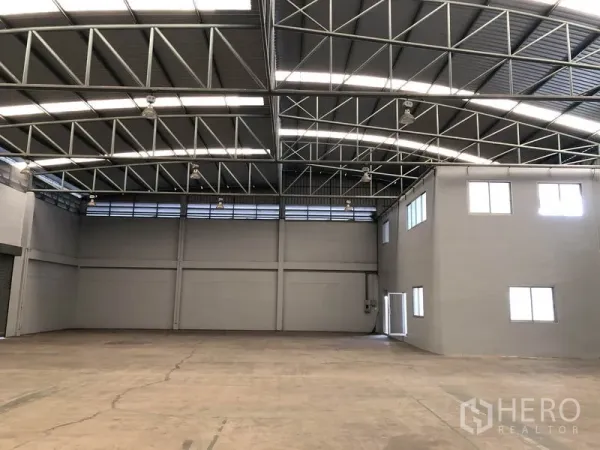 Factory for rent in Pathum Thani - Bright warehouse interior with steel beams, skylights and open floor for storage or production.