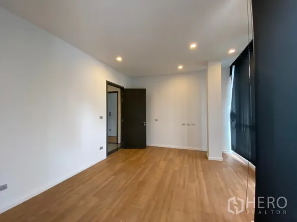 带办公室的家 出租或出售在Watthana, Bangkok - 明亮空置办公室，木纹地板、筒灯照明与深色窗帘。