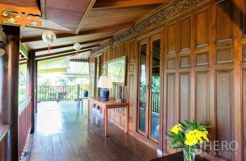 Detached House for rent in Bang Na, Bangkok - Shaded verandah with carved wood panels, console table and garden view.
