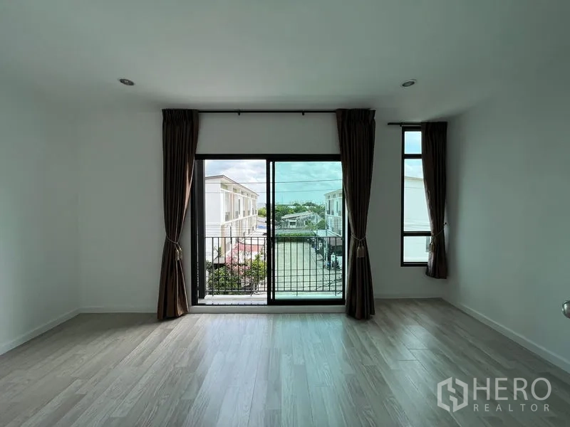 Townhouse for sale in Bang Kapi, Bangkok - Bright room with balcony doors and side windows facing the community.