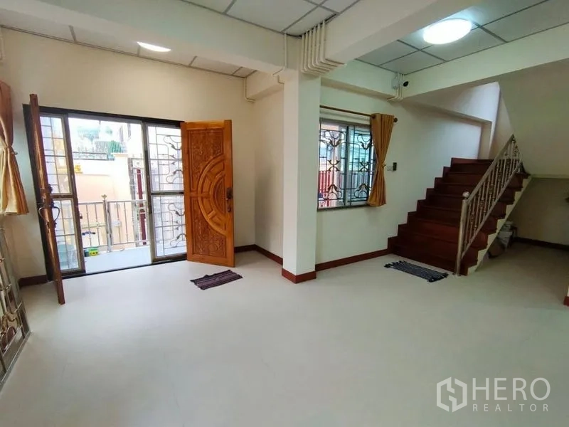 Detached House for rent in Khlong Toei, Bangkok - Open living area with staircase, wooden front door and access to a small balcony.