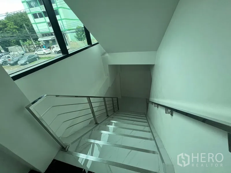 Office Space for rent or sale in Wang Thonglang, Bangkok - Staircase with stainless-steel handrail next to a large window overlooking the street.