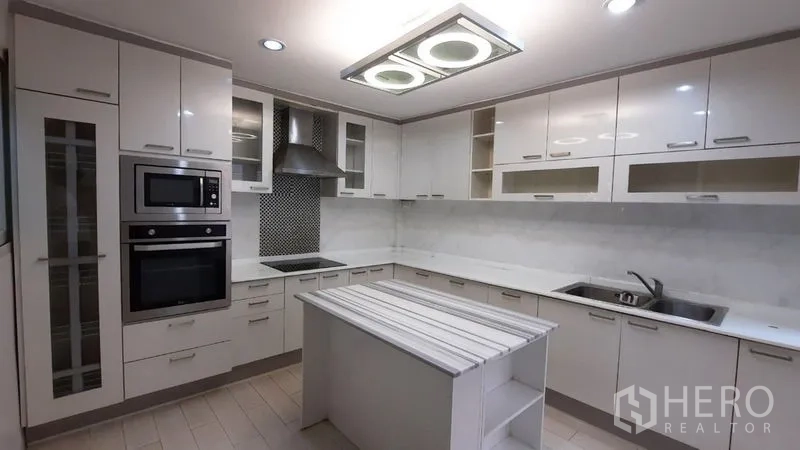 Townhouse for rent or sale in Suan Luang, Bangkok - Contemporary L-shaped kitchen with ample cabinetry and island bench.