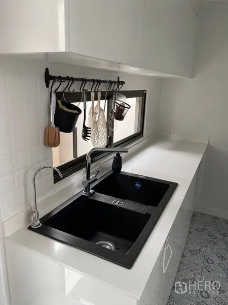 Townhouse for rent in Suan Luang, Bangkok - White pantry with double black sink, long countertop and utensil rack below a window.