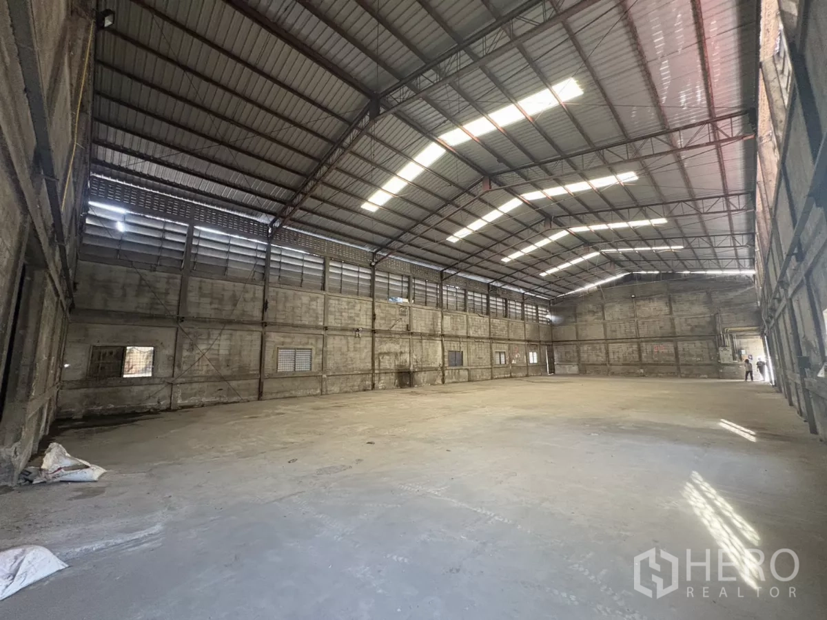 Warehouse for rent in Khlong Toei, Bangkok - Open storage hall with ventilated louver walls, natural light, and smooth concrete floor.