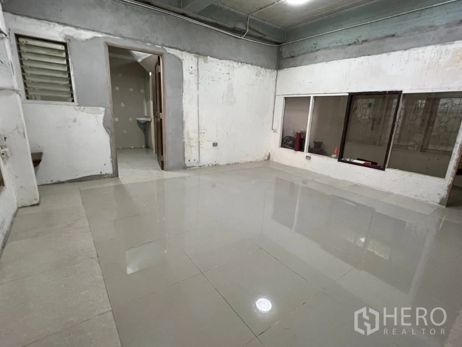 Warehouse for rent in Phra Pradaeng, Samut Prakan - Office room with tiled floor, internal windows, and a doorway leading to a washroom.