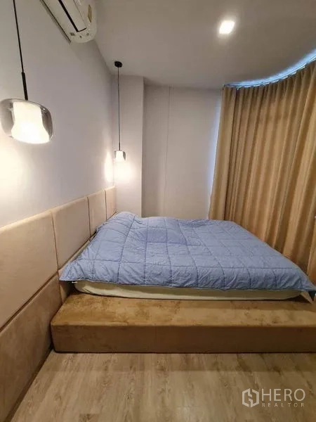 Condominium for rent - Close-up of upholstered headboard, pendant light and platform bed in neutral tones.