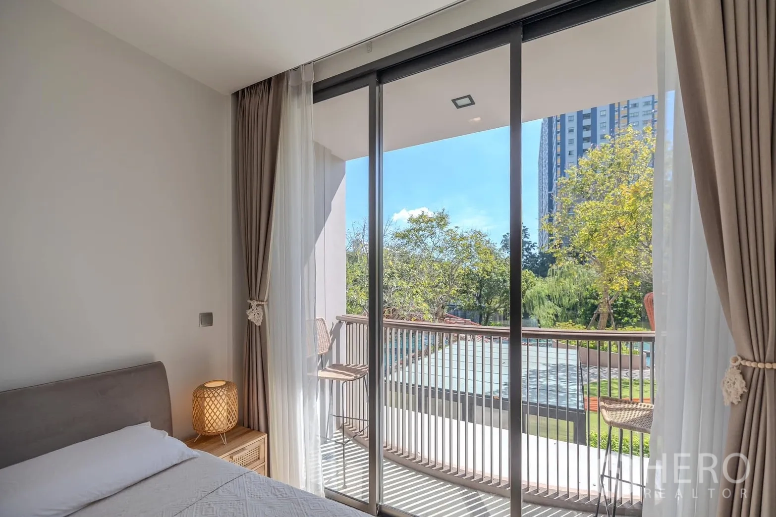 คอนโด for rent in Watthana, Bangkok - ห้องนอนเชื่อมต่อระเบียง มีเก้าอี้นั่ง ชมวิวต้นไม้และสระด้านล่าง