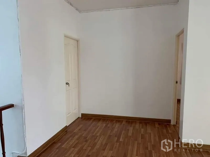 Detached House for sale in Sai Mai, Bangkok - Upstairs hallway leading to bedrooms with wooden floors and simple doors.