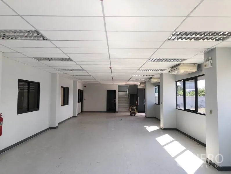 Factory for rent or sale in Bang Sao Thong, Samut Prakan - Ground-floor office inside the factory with tiled floors, drop ceiling, fluorescent lighting and a central staircase.