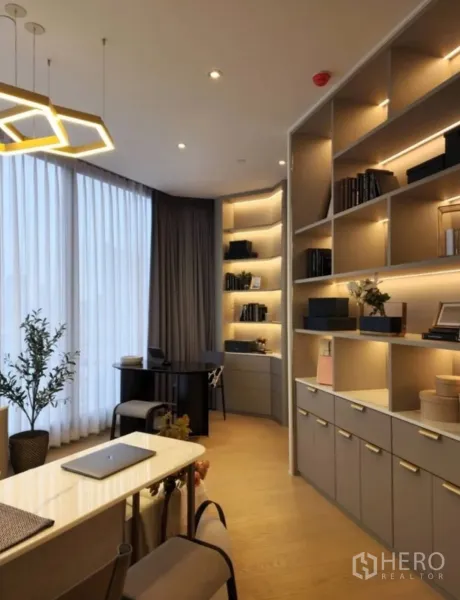 Condominium for rent in Din Daeng, Bangkok - Built-in illuminated shelving with a compact home office beside a large window.