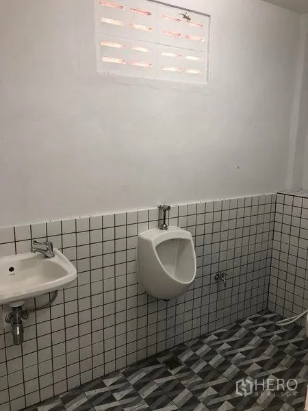 Warehouse for rent in Khlong Luang, Pathum Thani - Tiled restroom with a wall-mounted sink and urinal inside the warehouse.