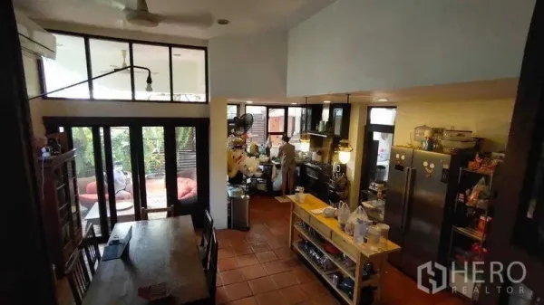 Detached House for sale in Suan Luang, Bangkok - Open kitchen with island, double‑door fridge and pendant lights connected to the dining area and patio.