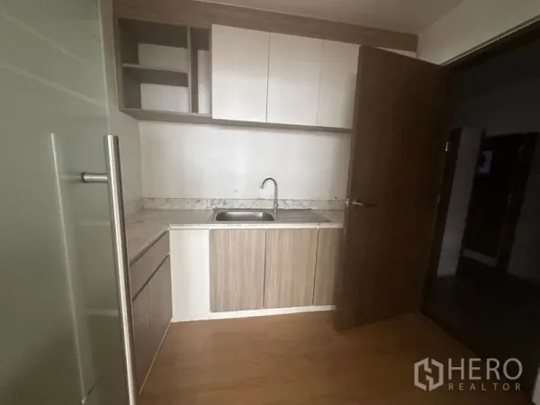 Office Space for rent in Bang Rak, Bangkok - Compact office pantry with sink, stone-look countertop, and upper and lower storage cabinets.