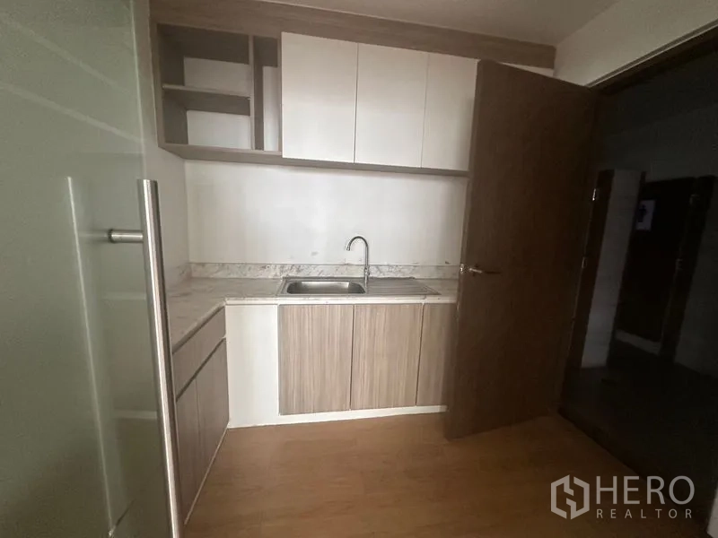 Office Space for rent in Bang Rak, Bangkok - Compact office pantry with sink, stone-look countertop, and upper and lower storage cabinets.
