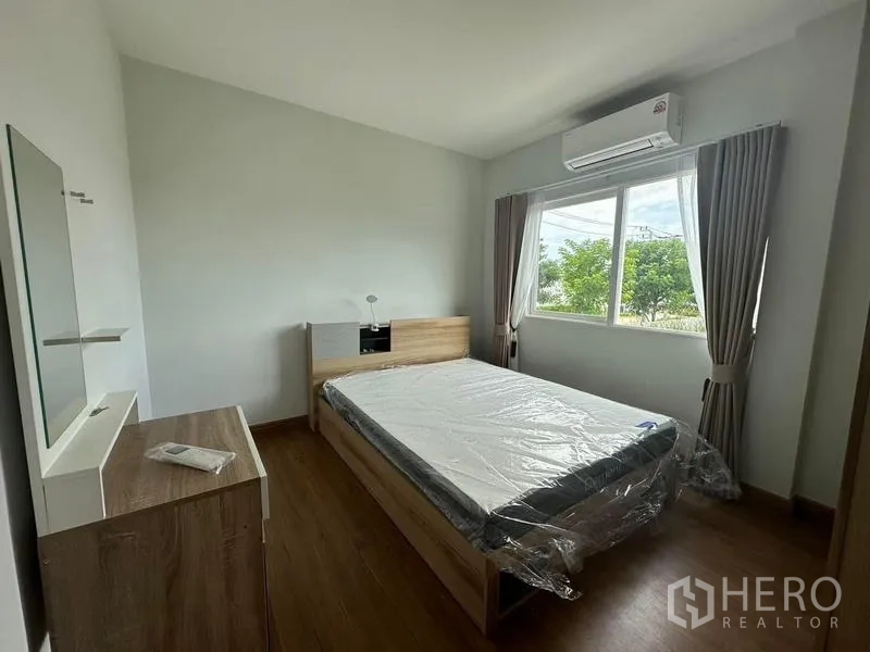 Detached House for rent in Bang Phli, Samut Prakan - Guest bedroom with double bed, dresser, large window, and AC overlooking greenery.