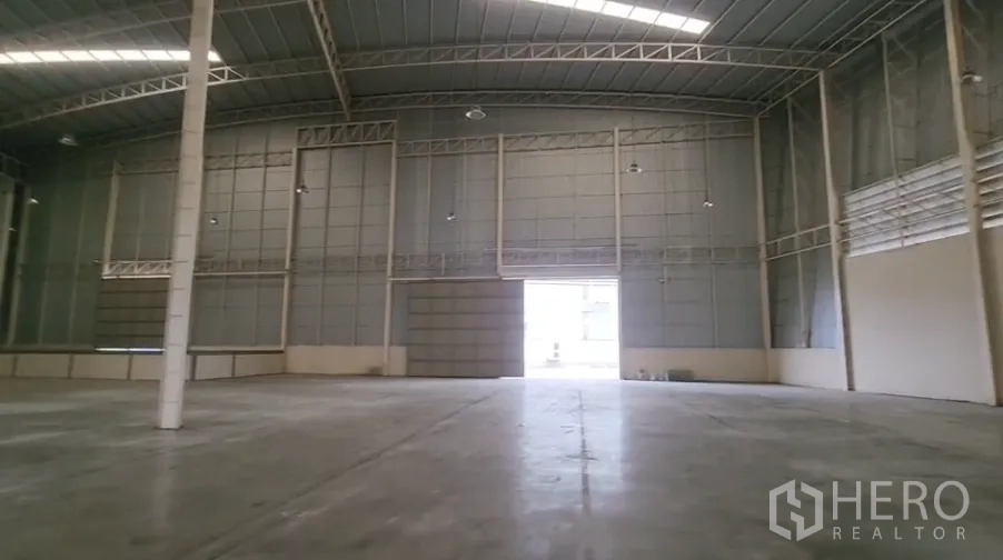 Warehouse for rent in Mueang Samut Sakhon, Samut Sakhon - Interior looking toward a wide loading door with smooth industrial flooring and tall walls.