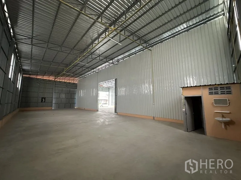 Warehouse for rent in Bueng Kum, Bangkok - Warehouse interior showing built-in restroom cubicle, sink and high ceiling.