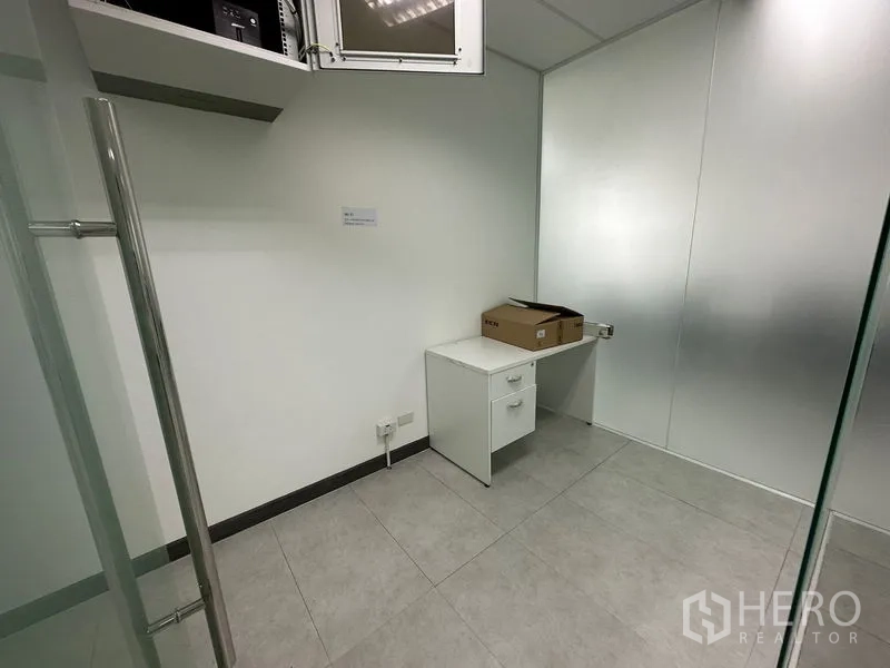Office Space for rent - Compact server or storage room with a small desk and overhead access panel.
