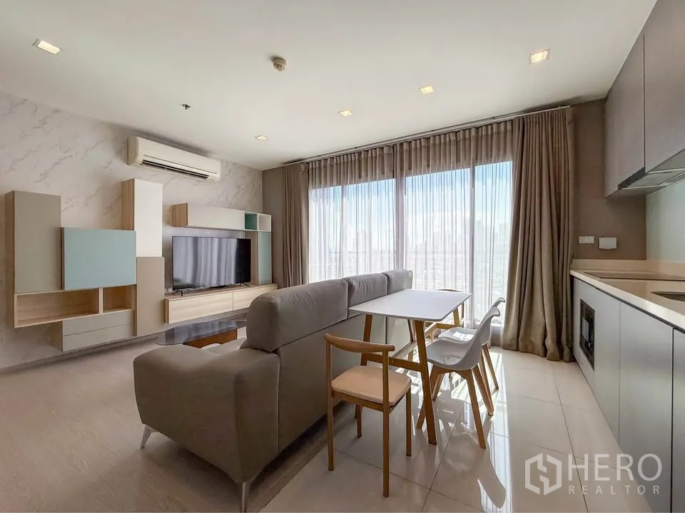 公寓 for rent in Khlong Toei, Bangkok - 开放式起居区，配 L 型沙发、餐桌、电视墙与一字型小厨房。