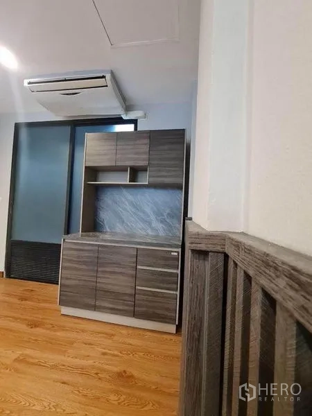 Townhouse for sale in Suan Luang, Bangkok - Compact pantry with grey wood cabinets beneath split air conditioner and sliding door.