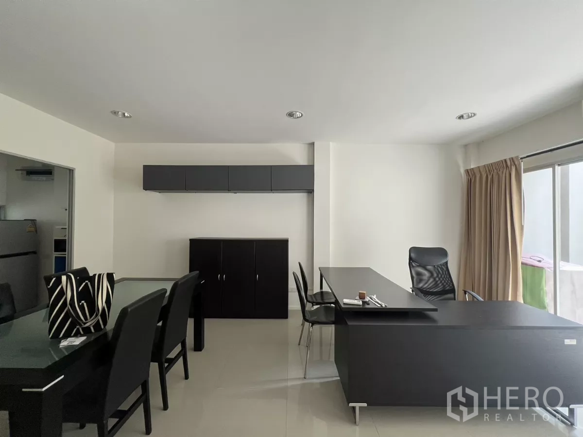 Townhouse for rent in Suan Luang, Bangkok - Workspace corner with wall cabinets and dining set in sleek dark tones.