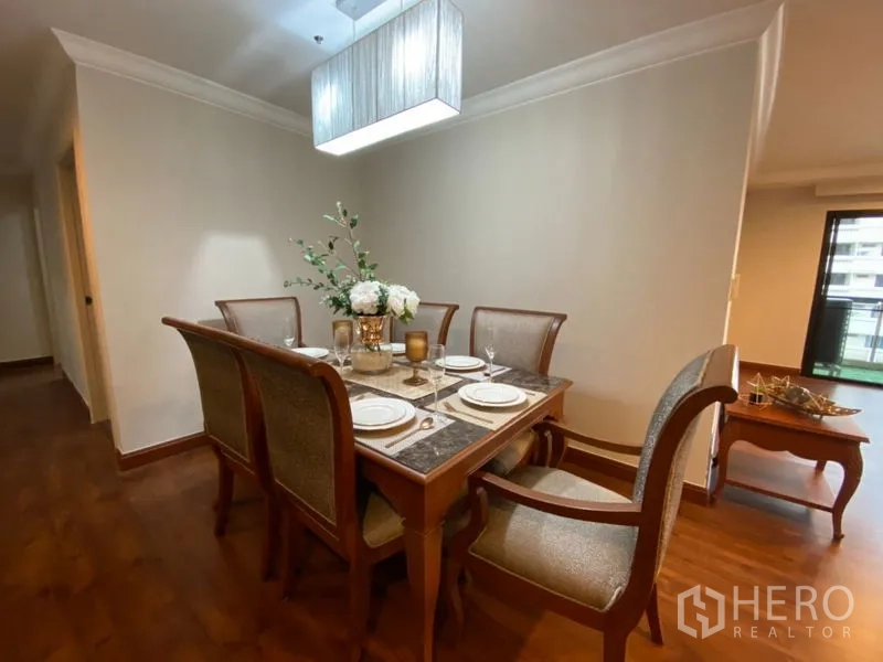 Condominium for rent in Watthana, Bangkok - Formal dining area with six-seat wooden table beneath a contemporary pendant light.