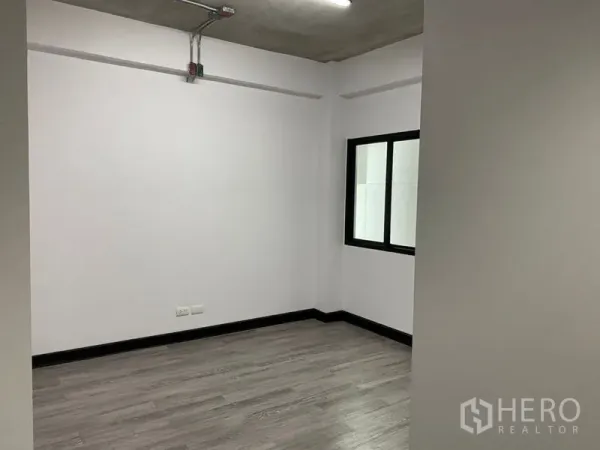 สำนักงาน ให้เช่า - ห้องมุมส่วนตัว ผนังสีขาว พื้นสีเทา มีหน้าต่างและท่อระบบบนเพดานแบบลอย