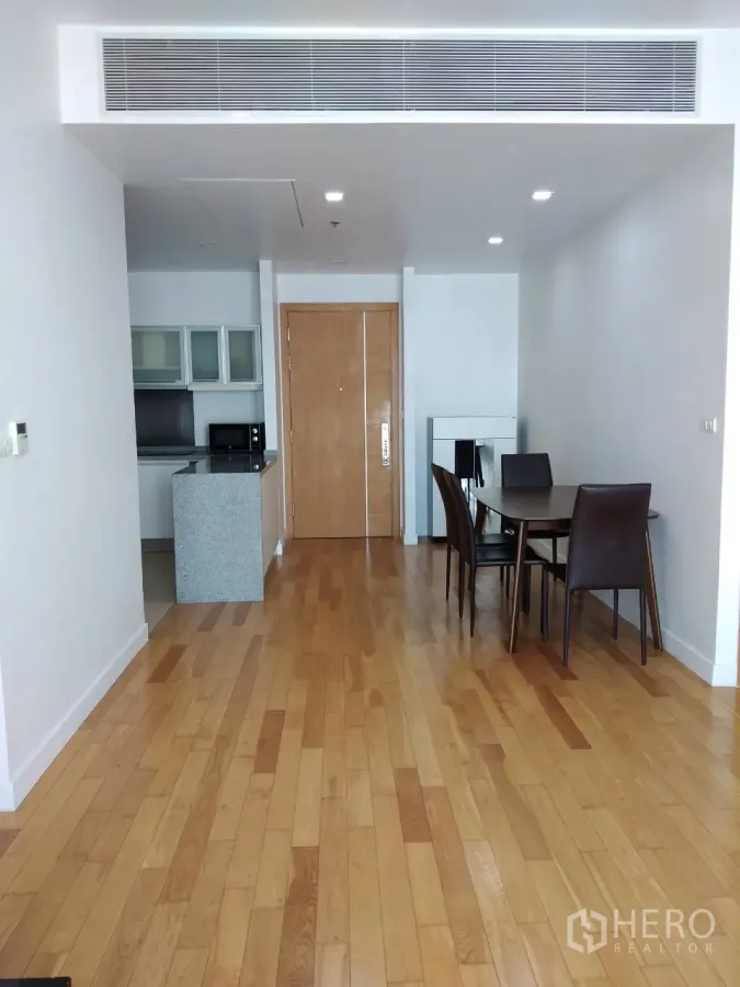 Condominium for rent in Khlong Toei, Bangkok - Open-plan living and dining with hardwood floors, recessed lighting, and a granite-top kitchen near the entrance.