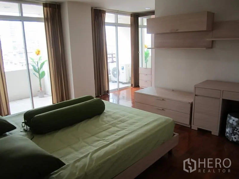公寓 出租在Bang Rak, Bangkok - 主卧铺绿色床品，大窗直通阳台，内置收纳与木地板。