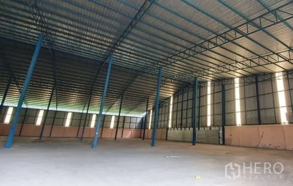 货栈 出租在Chaloem Phra Kiat, Nakhon Ratchasima - 斜角视图展示空置仓库地面、采光带与卷帘门。