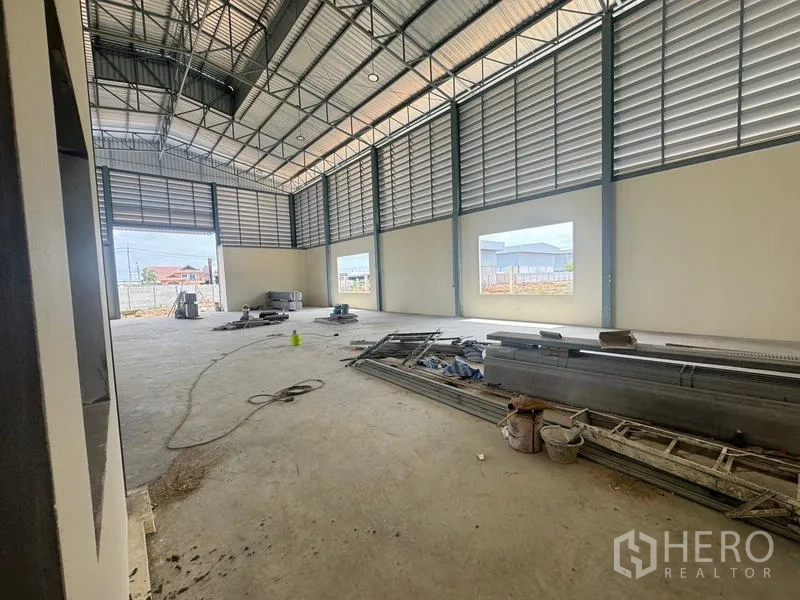 Warehouse for rent in Mueang Samut Prakan, Samut Prakan - Clear‑span warehouse floor with louvered ventilation panels and broad window openings.