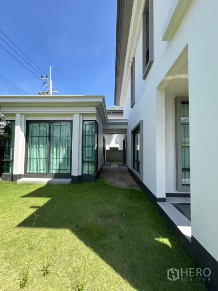 独立式住宅 出租或出售在Mueang Pathum Thani, Pathum Thani - 主楼与亭房之间的草地通道通向服务区。