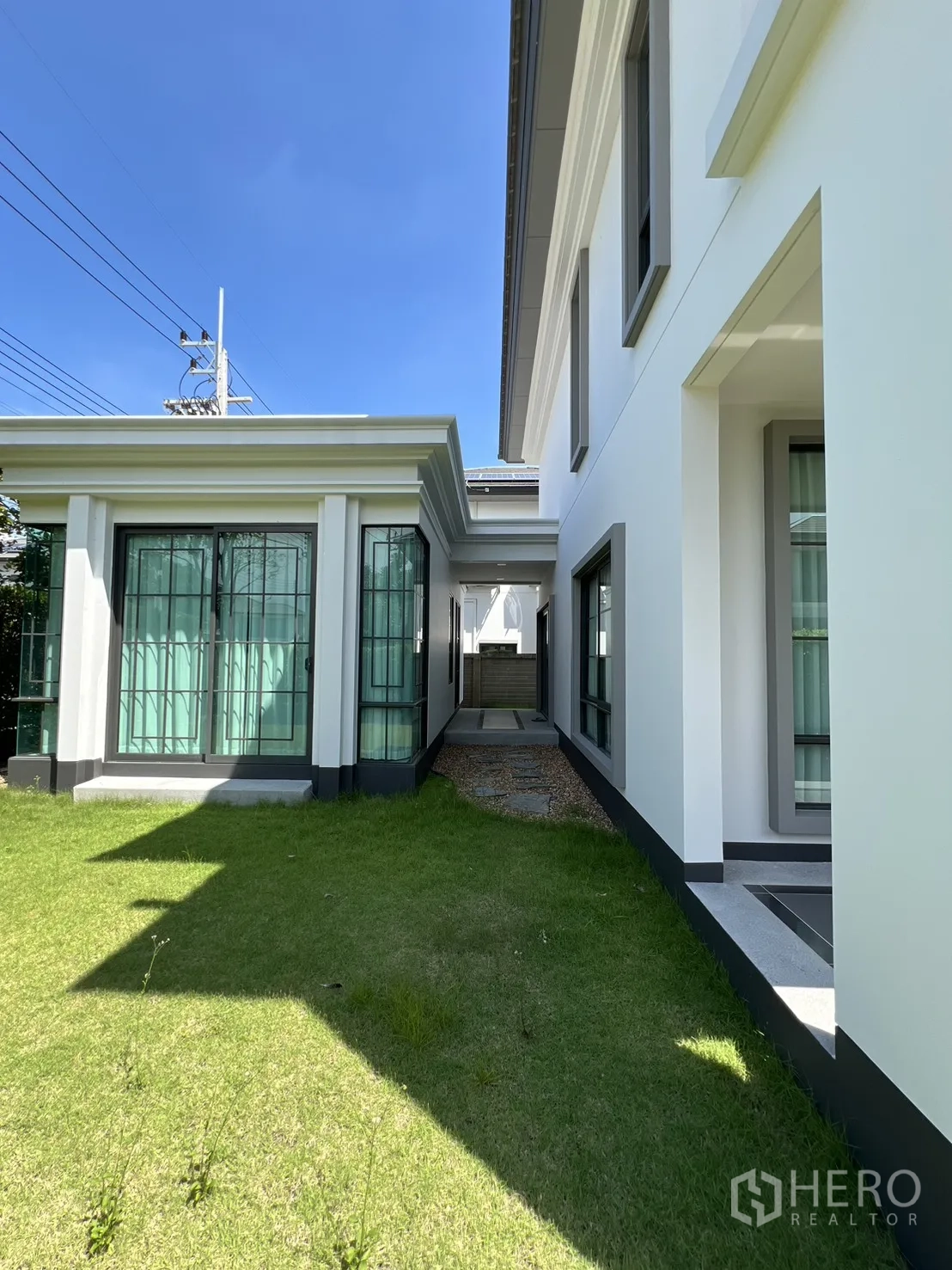 独立式住宅 出租或出售在Mueang Pathum Thani, Pathum Thani - 主楼与亭房之间的草地通道通向服务区。