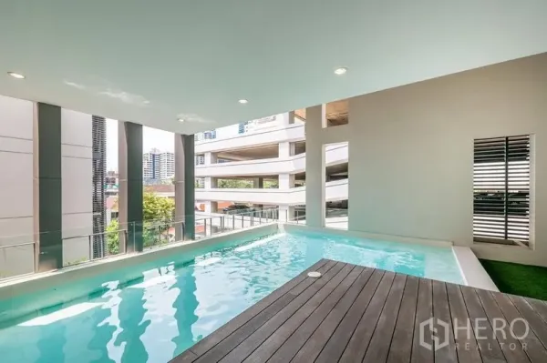 联排别墅 出租在Khlong Toei, Bangkok - 室内私人泳池与木质甲板，可见城市景观