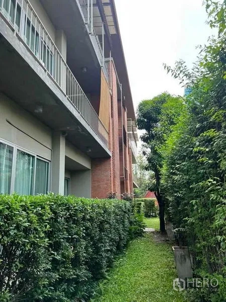 房间 出租 - 楼侧绿地与灌木篱笆，上方设有阳台。
