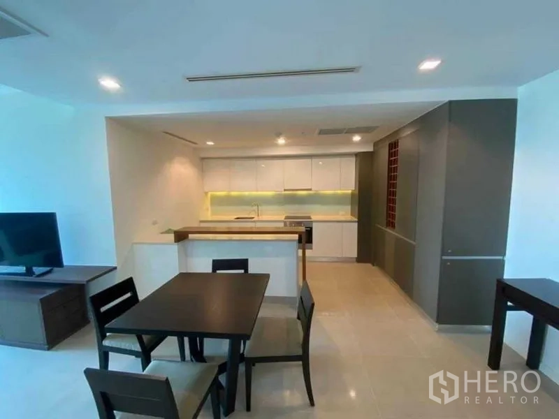 公寓 出租在Khlong San, Bangkok - 现代白色厨房，内置家电、餐桌与储物柜。