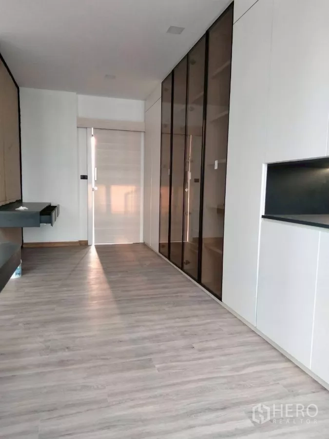 Townhouse for rent in Chatuchak, Bangkok - Spacious room featuring glass wardrobes and wood‑look flooring.