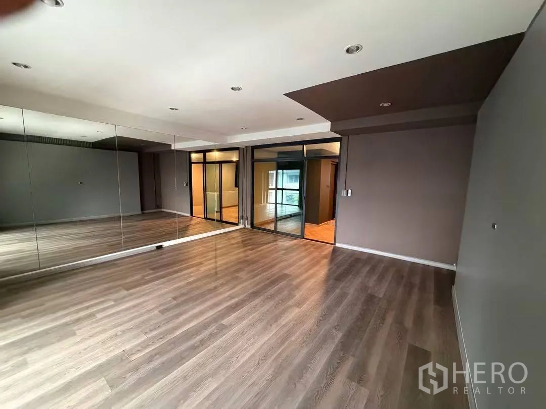Home Office for rent in Watthana, Bangkok - Large studio-style room with full-wall mirrors, sliding glass doors, and wood-look floors.