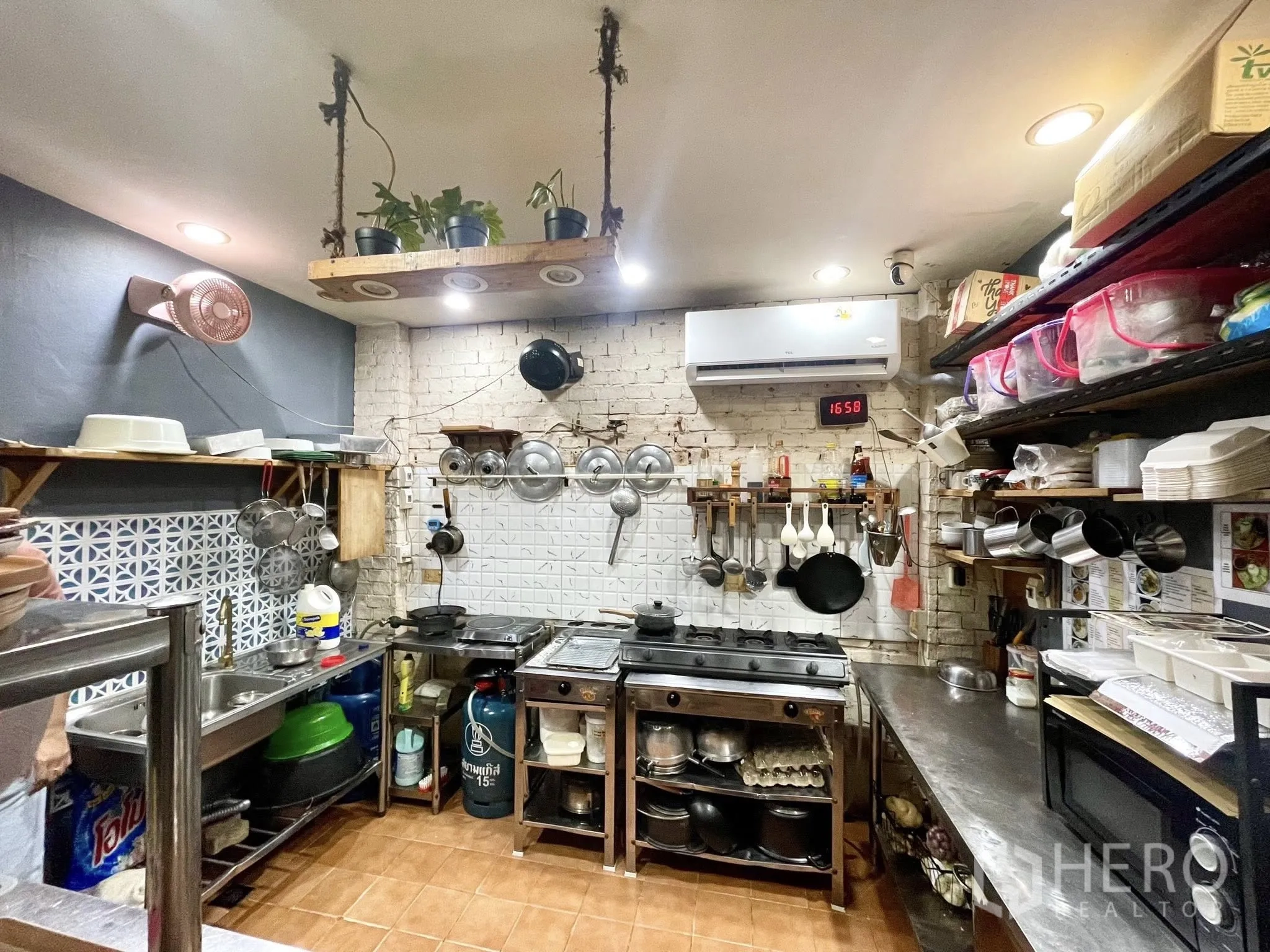 Retail Space for rent in Watthana, Bangkok - Commercial kitchen with gas stove, stainless steel prep counters, wall shelves, and air conditioning.
