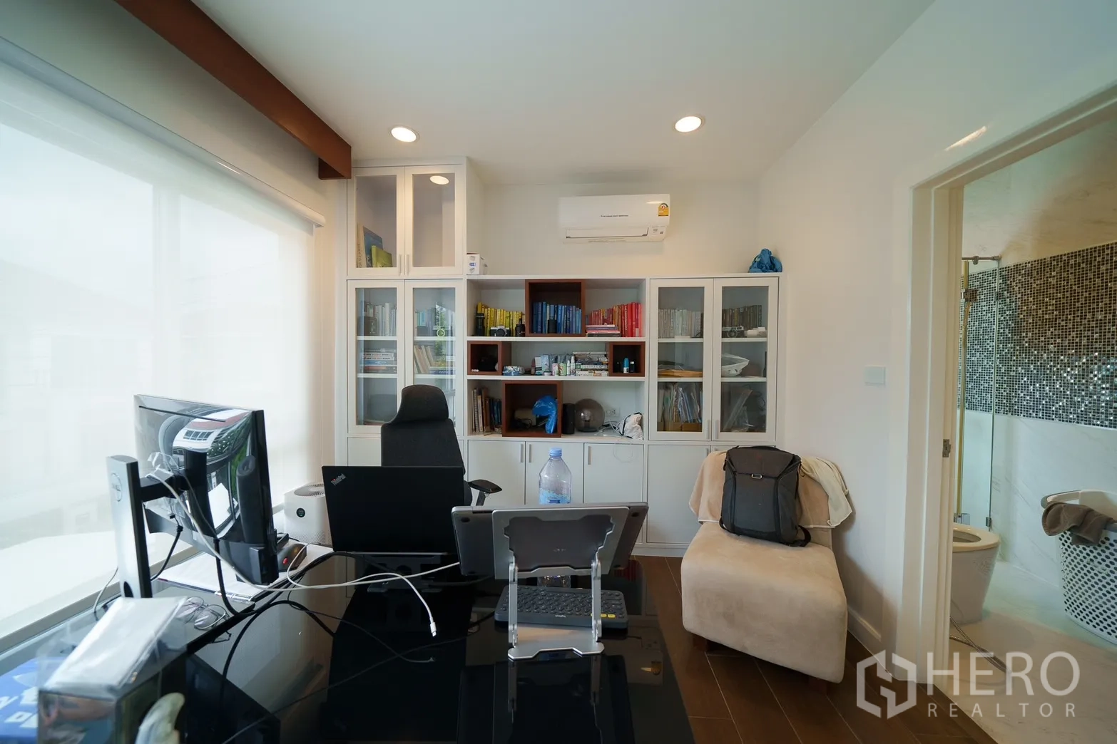 Detached House for rent or sale in Saphan Sung, Bangkok - Home office with built‑in glass cabinets, large window and direct access to a bathroom.