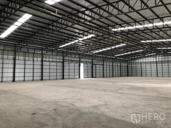 货栈 出租在Pathum Thani - 仓库内部宽敞，高钢桁架屋顶，采光带与平整混凝土地面。