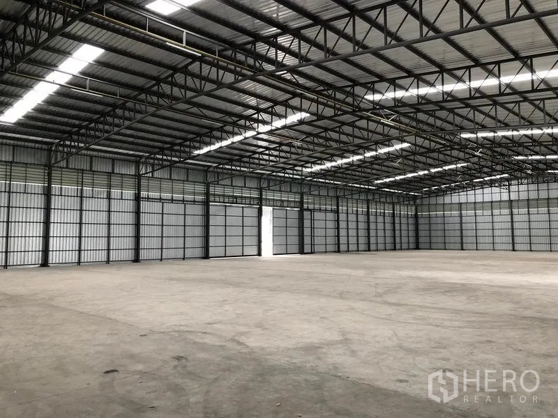 货栈 出租在Pathum Thani - 仓库内部宽敞，高钢桁架屋顶，采光带与平整混凝土地面。