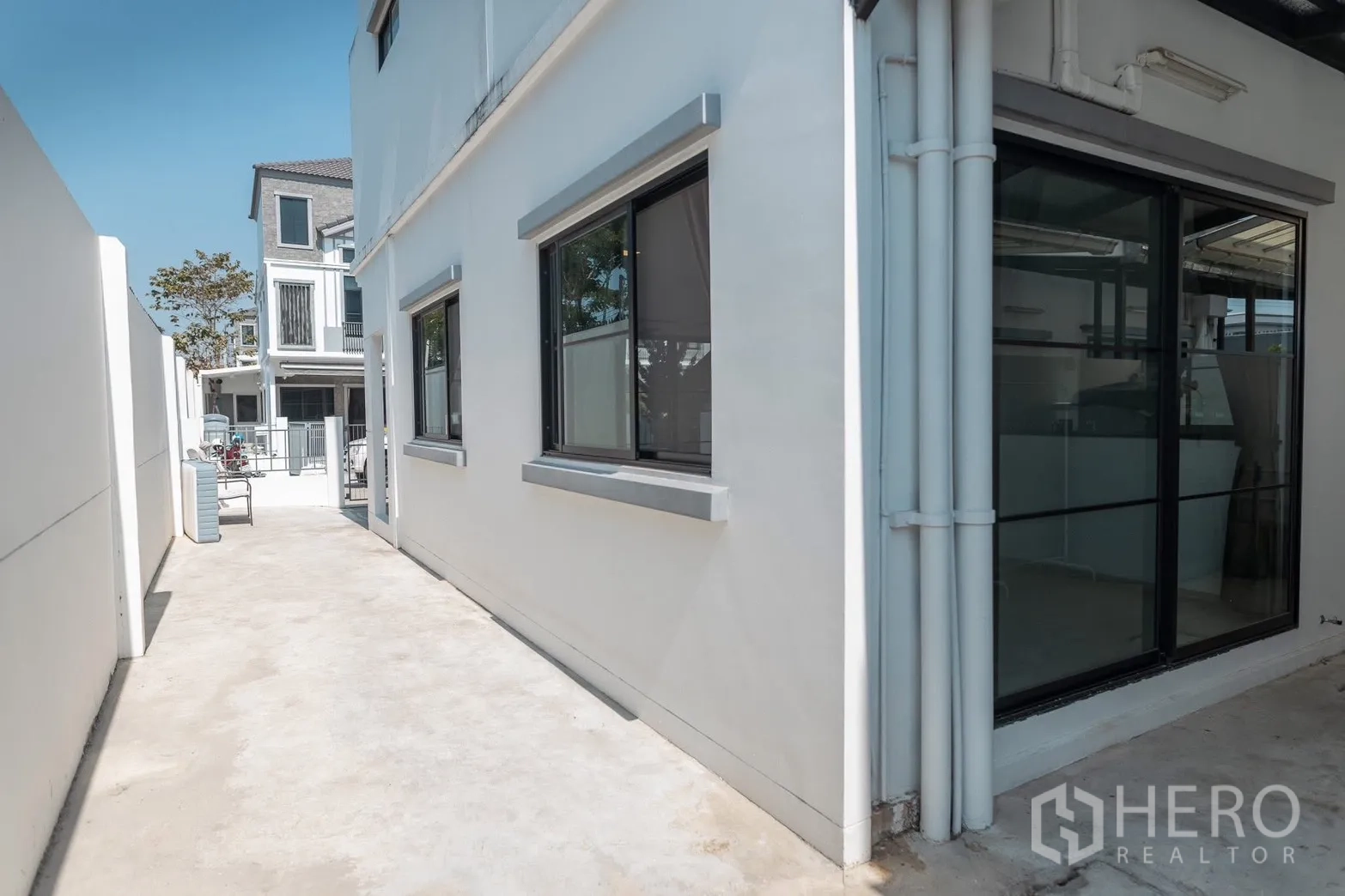 ทาวน์เฮาส์ for rent in Bang Phli, Samut Prakan - ทางเดินข้างบ้านของทาวน์เฮ้าส์สีขาวพร้อมประตูกระจกบานเลื่อนและหน้าต่าง